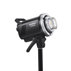 1656491253_847 The Godox MS300V studio strobe lamp is mounted on a black stand and tilted so that its controls and bracket are visible against a white background.