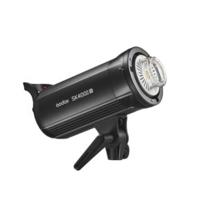 1658906847_150 Musta Godox SK400II-V -studiostroboskooppivalaisin, jossa on kahva ja kiinnitysteline, on esillä kulmassa, ja sen lamppu ja etuosa näkyvät valkoista taustaa vasten.