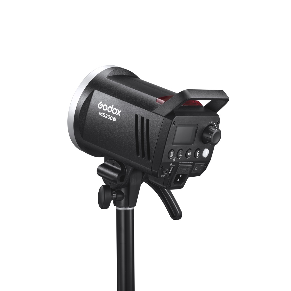 1682497680_009 Musta Godox MS200V -studiostroboskooppivalaisin on asennettu jalustalle, ja sen takaohjauspaneeli, säätönupit, tuuletusaukot ja kahva näkyvät valkoista taustaa vasten.