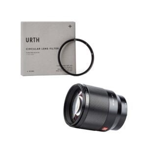 Viltrox AF 85mm f/1.8 II - Nikon Z + URTH Kit (UV Plus+) sisältää mustan, sylinterimäisen kameran objektiivin ja ohuen pyöreän UV-suodattimen, joka on kuvassa harmaan URTH-sirkulaarisen objektiivisuodattimen laatikon vieressä.