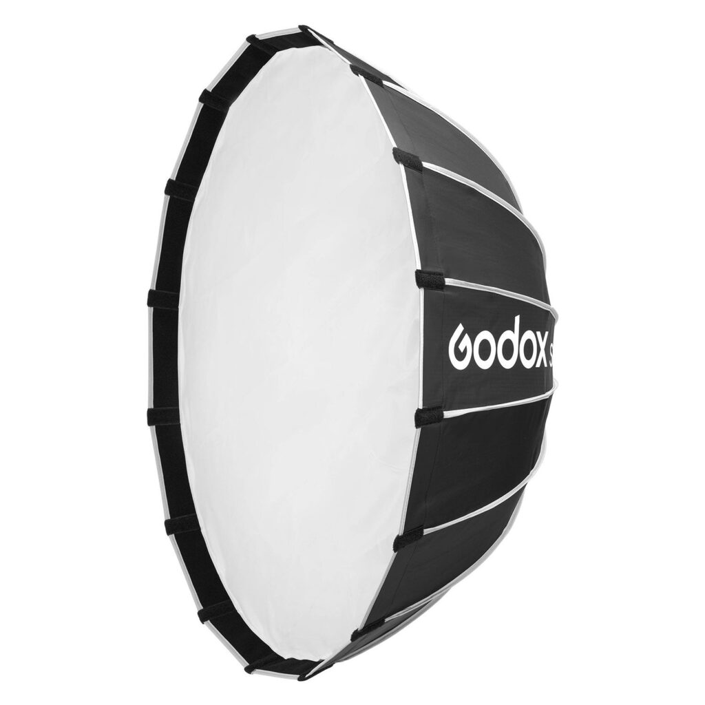 1705321833_722 Godox Multifunctional Softbox S85T on suuri, pyöreä valokuvausvalaistuksen softbox, jossa on valkoinen diffuusori edessä ja mustat sivut, joissa on Godoxin logo.