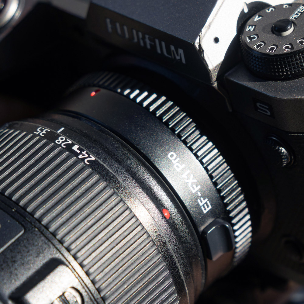 1707466182_707 Lähikuva Fujifilm-kamerasta, johon on kiinnitetty Viltrox EF-FX1 PRO Autofocus Adapter -adapteri, jossa korostuvat yksityiskohtaiset merkinnät ja tekstuurit sekä adapterissa että kameran rungossa.
