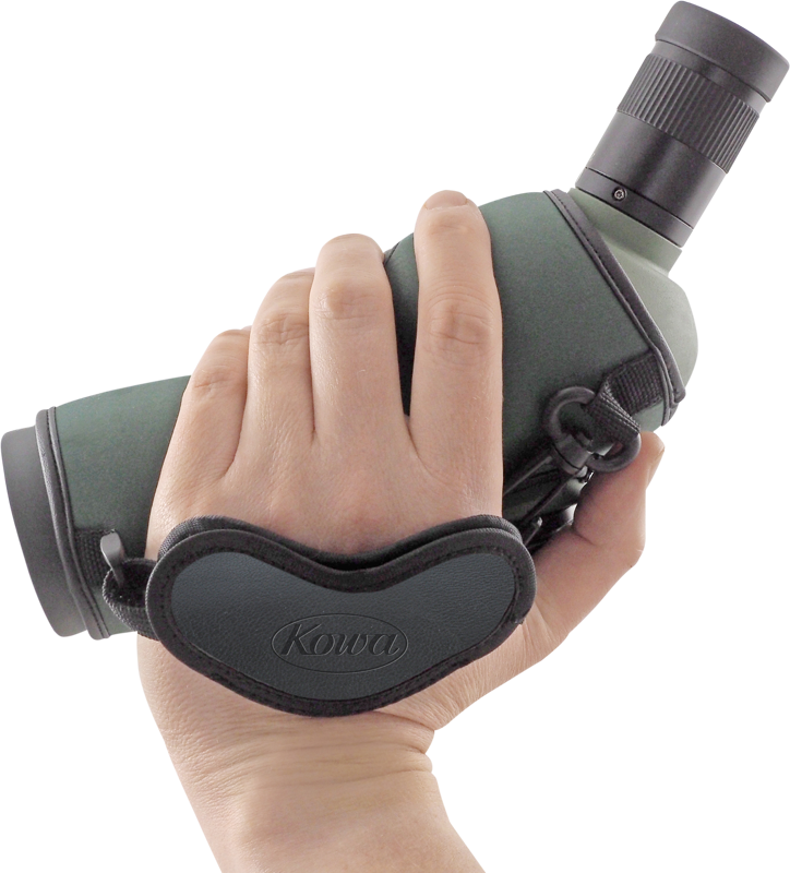 800q-02_109758 Käsi, joka pitää tähystintä, johon on kiinnitetty KOWA Hand Strap for Spottingscope -käsihihna, jossa on vihreää ja mustaa väriä valkoista taustaa vasten.