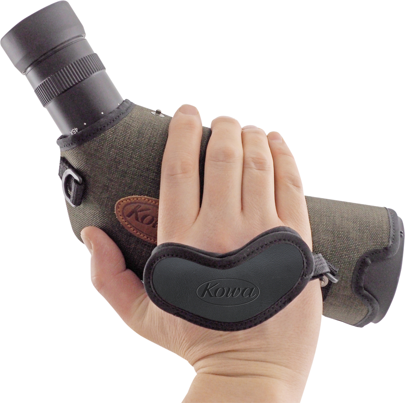 800q-03_109758 Käsi pitelee vihreää Kowa-kiikaritähtäintä, joka on varustettu mustalla sydämenmuotoisella KOWA Hand Strap for Spottingscope -käsihihnalla, valkoisella taustalla.