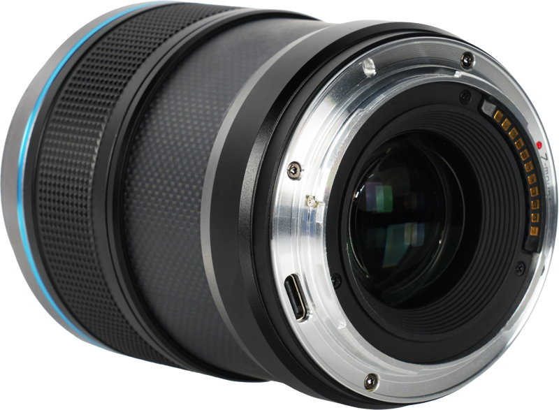 800q-04_126719 Sirui Sniper 23mm f/1.2 AF E-mount (Musta) -kameran objektiivin lähikuvassa näkyy sen metallinen kiinnitysrengas, elektroniset koskettimet ja osa tarkennusrenkaasta valkoista taustaa vasten.