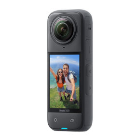 Insta360_X4_002 Lähikuva Insta360 X4 360 -kamerasta ja sen kosketusnäytöstä, jossa hymyilevä pariskunta ottaa selfietä ulkona meren ja rehevän vehreyden kanssa taustalla.