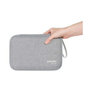Insta360_X4_016 Kädessä on Insta360 X4 Carry Case, suorakulmainen harmaa kangaskotelo, jossa on vetoketju ja silmukka ja jonka oikeassa alakulmassa on valkoisella teksti "Insta360 Think bold.".