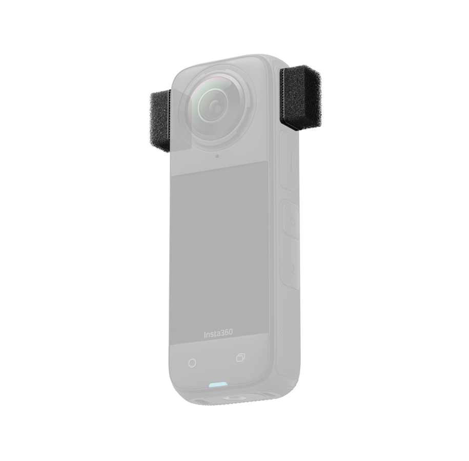 Insta360_X4_029 Insta360 X4 Mic Wind Muff, pieni musta suorakulmainen vaahtomuovisuojus, on kuvassa kiinnitettynä Insta360-kameran ylä- ja sivumikrofoneihin tuulen aiheuttaman melun vähentämiseksi. Kamera on häivytetty Mic Wind Muffien korostamiseksi.