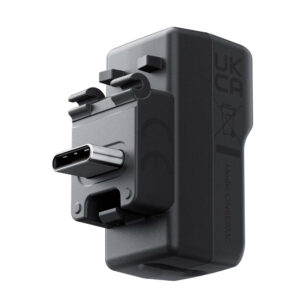 Insta360_X4_043 The Insta360 X4 Mic Adapter is a black USB-C wall charger with UKCA certification, regulatory icons and a visible USB-C port on the front. Additional labelling and model number on the side.