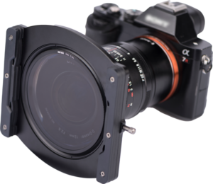 Nisi Filter Holder Kit for Laowa 12mm f/2.8 on kiinnitetty digitaalikameran objektiiviin, ja se on kuvassa asennettuna objektiivin etupuolelle valkoista taustaa vasten.