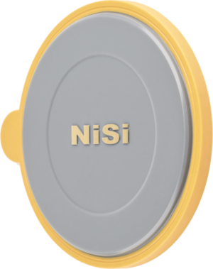 800q-01_112204 The NiSi Lens Cap for M75 Holder is a round, flat, grey cap with a gold NiSi lettering and a yellow border against a light background.