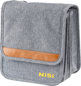 800q-01_113464 NiSi Filter Pouch Pro Caddy 150mm on harmaasta kankaasta valmistettu kameran tarvikelaukku, jossa on ruskea nahkainen korostus ja keltainen "NiSi" etuläpän päällä valkoista taustaa vasten.