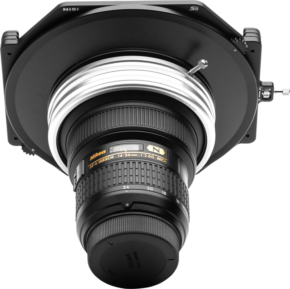 800q-01_115176 Lähikuva NiSi Filter Holder S6 Kit True Color for Nikon 14-24mm f/2.8 levysuodin pidike, joka on kiinnitetty Nikonin objektiiviin ja kuvattu edestä vaaleanharmaata taustaa vasten.
