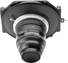 800q-01_115183 Close-up of the NiSi filter holder S6 Kit True Color for Fujinon XF 8-16mm f/2.8 with the disc filter holder attached to the lens, viewed from the front against a light grey background with the lens markings and details visible.