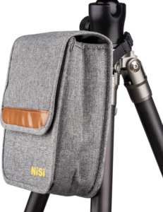 Harmaa NiSi Filter Holder S6 Pouch -suojapussi, jossa on ruskea korostus, on kiinnitetty mustan jalustan jalustaan valkoista taustaa vasten.