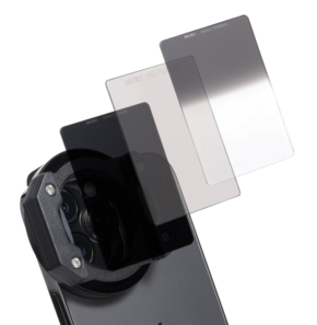Lähikuva NiSi Filter IP-A Landscape Kit for iPhone -suodattimesta, jossa on objektiivikiinnike ja kolme kaltevuusfiltteriä älypuhelinkameran yläpuolella, valkoista taustaa vasten.