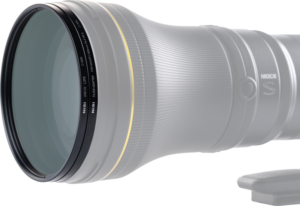 Lähikuva NiSi Filter UHD UV L395 For Nikkor Z 800mm f/6.3 VR S -UV suodin, jossa näkyy kultainen rengas etuelementin lähellä ja NIKKOR S -merkinnät, kiinnitettynä jalustakiinnikkeeseen, jossa on kuvioitu tarkennusrengas.