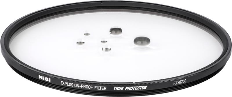 800q-02_118806 Lähikuva NiSi Cine -suodattimesta Explosion Proof / True Protector FJ28250 Fujinon Premista 28-100 & 80-250:lle, joka makaa litteänä, vesipisaroita sen kirkkaalla pinnalla, reunassa merkinnät TRUE PROTECTOR ja EXPLOSION-PROOF FILTER.