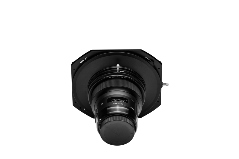 800q-03_109694 NiSi Filter S5 Adapter for Sigma 14mm f/1.8 (vain adapteri) on kuvattu edestä, asennettuna suureen, litteään, mustaan, kahdeksankulmaiseen objektiivilevyyn, jossa on suojakorkki, valkoista taustaa vasten.