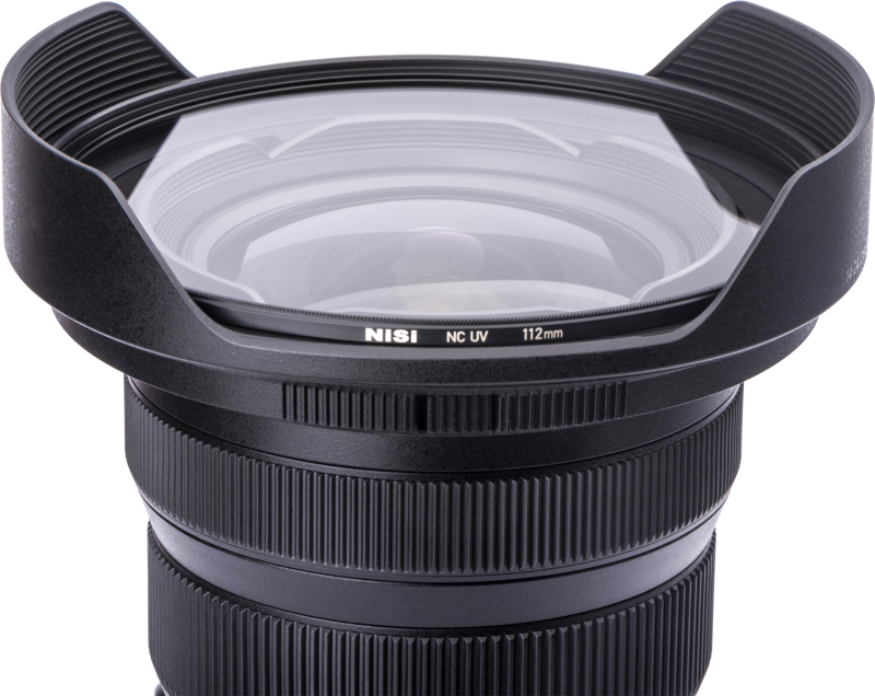 800q-03_114918 Lähikuva mustasta kameran objektiivista, jossa on laajakulmahuppu ja NiSi NC UV 112mm Filter For Nikon Z 14-24mm f/2.8 -UV suodin -etiketti suodattimessa valkoista taustaa vasten.