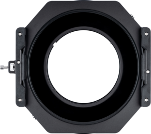 800q-03_115177 NiSi Filter Holder S6 Kit True Color for Tamron 15-30mm f/2.8 on musta, pyöreä suodattimen pidike, jossa on neliönmuotoinen kehys, ylhäältä katsottuna vaaleaa taustaa vasten. Siinä on sivukiinnikkeet ja avoin keskiosa kameran objektiivin suodattimien asettamista varten.