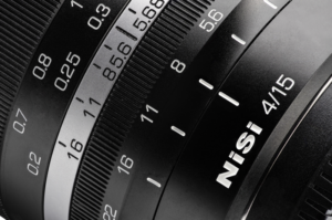 800q-03_115650 Lähikuva mustasta NiSi 15mm f/4 L-Mount -objektiivista, jossa näkyy yksityiskohtaiset tarkennus- ja aukkomerkinnät numeroineen ja yksikköineen sekä näkyvät kuvioidut pitorenkaat.