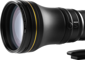 Lähikuva NiSi-suodattimesta UHD UV L395, joka on kiinnitetty Nikkor Z 800mm f/6.3 VR S -objektiiviin, jossa on kuvioitu kahva ja keltainen korostusrengas, kiinnitettynä jalustan kaulukseen valkoista taustaa vasten.
