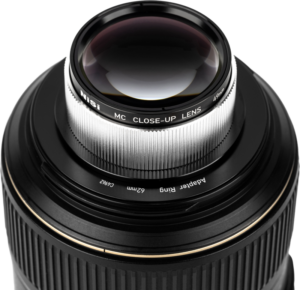 Lähikuva kameran objektiivista, johon on kiinnitetty NiSi Close Up Lens Kit NC 49mm -lähilinssi, jossa on yksityiskohtaiset urat ja lasielementit.
