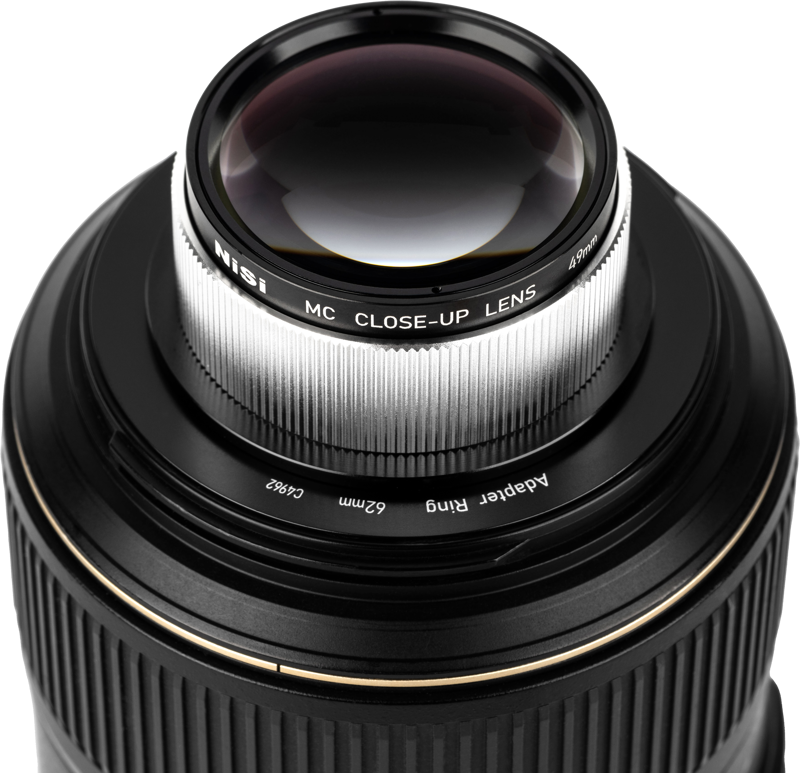 Lähikuva kameran objektiivista, johon on kiinnitetty NiSi Close Up Lens Kit NC 49mm -lähilinssi, jossa on yksityiskohtaiset urat ja lasielementit.