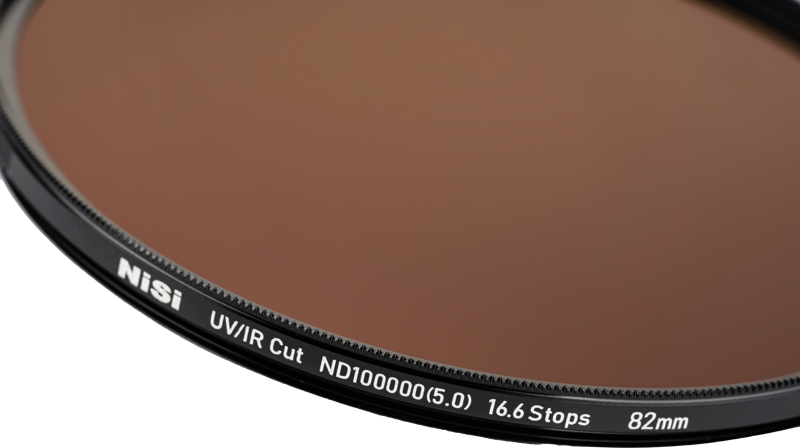 800q-03_124344 Lähikuva NiSi Pro Nano IR ND100000 77mm harmaasuodin linssisuodattimesta, jossa korostuu teksti ja yksityiskohdat sen mustassa metallireunassa vaaleaa taustaa vasten.