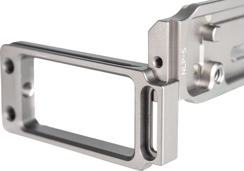 800q-04_119671 Lähikuva NiSi Universal Adjustable L-Plate NLP-S -metallirakenteisesta, suorakulmaisesta, tarkkaan työstetystä kamerakannattimesta, jossa on näkyvät ruuvit, kaiverrettu NLP-S-merkintä toisella puolella ja mattahopea pinta.