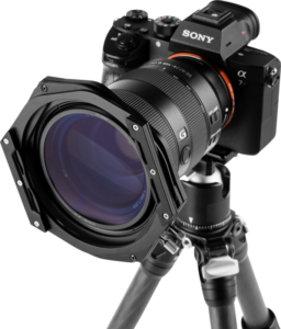 800q-05_112606 Sony Alpha -kamera, jossa on suuri objektiivi ja NiSi Switch -suodattimen pidike 100 mm, on asennettu jalustalle, edestä katsottuna tavallista taustaa vasten.