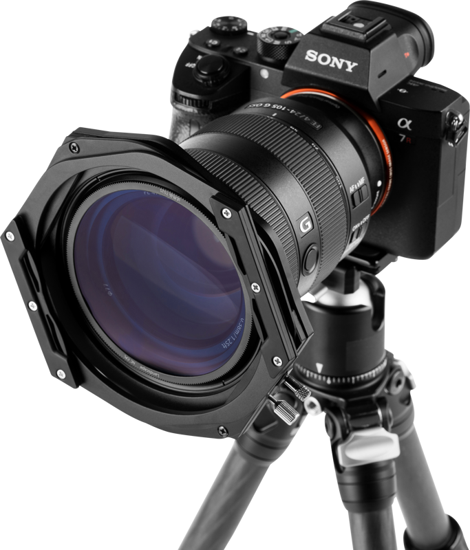 800q-05_112606 Sony Alpha -kamera, jossa on suuri objektiivi ja NiSi Switch -suodattimen pidike 100 mm, on asennettu jalustalle, edestä katsottuna tavallista taustaa vasten.