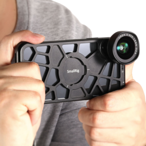800q-05_113861 Joku pitää iPhone X/XS:ää mustassa, lujassa SmallRig 2204 Pocket Mobile Cage -mobiilihäkissä, johon on kiinnitetty laajakulmaobjektiivi, ja valmistautuu kuvaamaan valokuvaa tai videota.