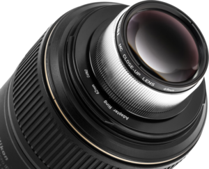 Lähikuva NiSi Close Up Lens Kit NC 49mm -lähilinssi kiinnitettynä kameran objektiiviin sovitinrenkaalla, korostaen objektiivin ja metalliosien yksityiskohtaisia kuvioita.