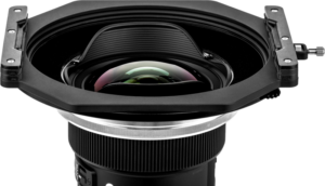 Lähikuva NiSi-suodattimen pidikkeestä S6 Alpha Kit for Sigma 14mm f/1.4 DG DN -levysuodin pidike, jossa on suuri kaareva lasielementti ja suorakulmainen huppu valkoista taustaa vasten.