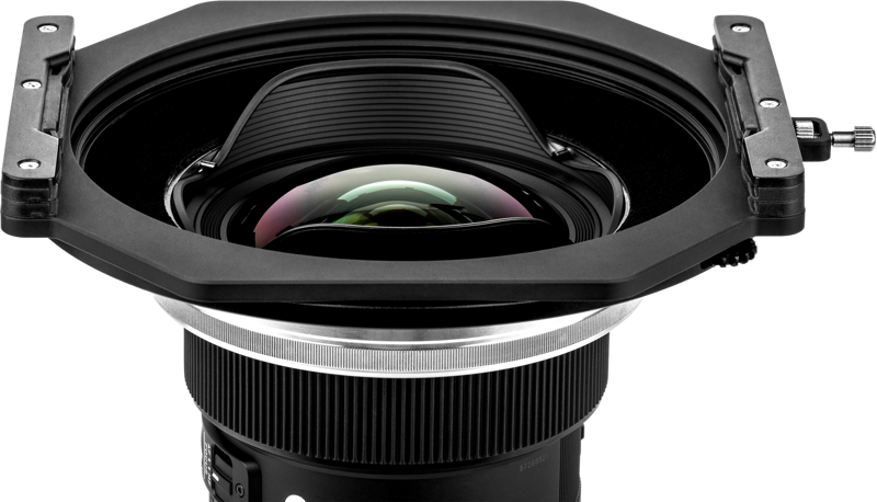 Lähikuva NiSi-suodattimen pidikkeestä S6 Alpha Kit for Sigma 14mm f/1.4 DG DN -levysuodin pidike, jossa on suuri kaareva lasielementti ja suorakulmainen huppu valkoista taustaa vasten.