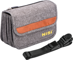 800q-115223 NiSi Filter Pouch Pro 100mm Caddy on harmaasta kankaasta valmistettu kameran tarvikepussi, jossa on ruskea aksentti ja keltainen NiSi-logo, kuvassa mustan säädettävän hihnan ja muoviklipsin vieressä.