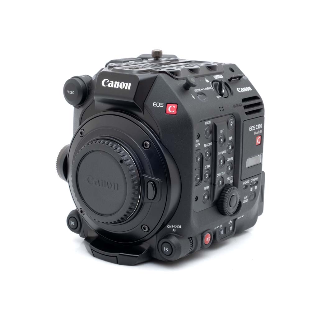 Canon C300 mark III-3 Canon EOS C300 Mark III (18h kuvattu, sis.ALV24%, Takuu 12kk) - Käytetty elokuvakamerarunko on esitetty etupuolelta, jossa näkyy erilaisia painikkeita, valitsimia ja portteja. Ei objektiivia kiinnitettynä.