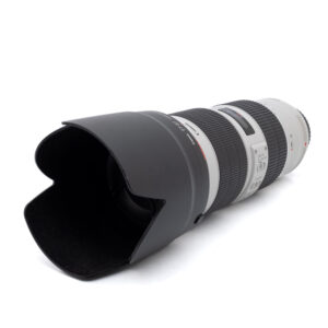 Canon EF 70-200mm f/2.8 L IS USM III (Kunto K5) - Käytetty telezoom-objektiivi, johon on kiinnitetty musta vastavalosuoja, on kuvassa kyljellään valkoista taustaa vasten.