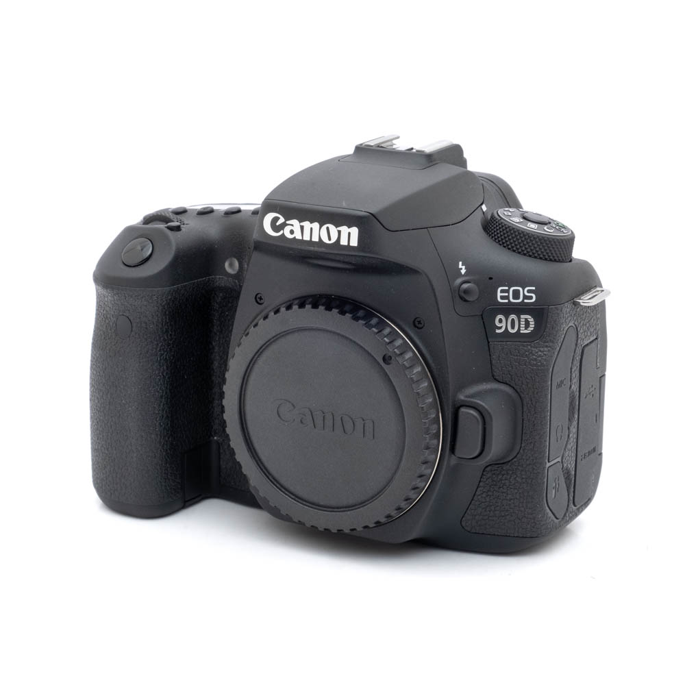 Canon EOS 90D-1 Canon EOS 90D (SC 12 000) - Käytetty kamerarunko, ilman objektiivia, vinossa valkoisella pohjalla.