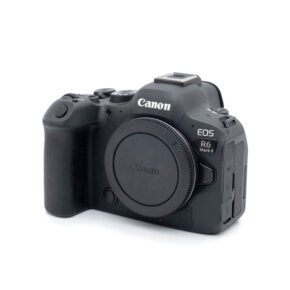 Canon R6 II-1 Canon EOS R6 II (SC 1000, Kunto K5) - Käytetty peilitön kamerarunko mustana näkyy kuvakulmassa, jossa näkyy kahva, ohjauspainikkeet ja objektiivin kiinnityssuojus ilman kiinnitettyä objektiivia.