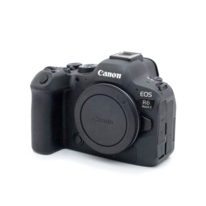 Canon R6 II-1 Canon EOS R6 II (SC 1000, Kunto K5) - Käytetty peilitön kamerarunko mustana näkyy kuvakulmassa, jossa näkyy kahva, ohjauspainikkeet ja objektiivin kiinnityssuojus ilman kiinnitettyä objektiivia.