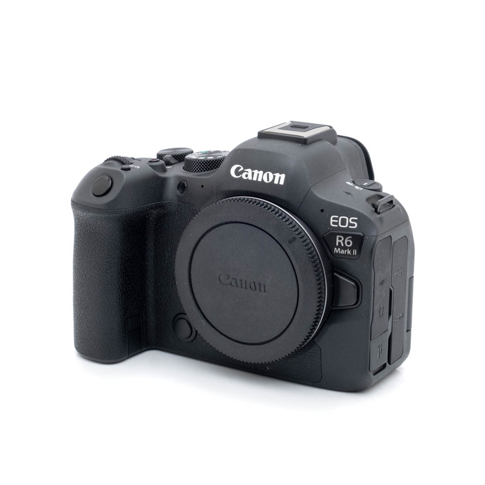 Canon R6 II-1 Canon EOS R6 II (SC 1000, Kunto K5) - Käytetty peilitön kamerarunko mustana näkyy kuvakulmassa, jossa näkyy kahva, ohjauspainikkeet ja objektiivin kiinnityssuojus ilman kiinnitettyä objektiivia.