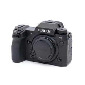 Fujifilm X-H2s-2045-1 Käytetty Fujifilm X-H2s -digitaalikamerarunko (SC 10000, K5, 12 kuukauden takuu, alv 24 %) on esitetty kolmivartalokuvassa ilman objektiivia; siinä on musta viimeistely, näkyvät valintakiekot ja kuvioitu kahva.