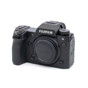 Fujifilm X-H2s-2045-1 Käytetty Fujifilm X-H2s -digitaalikamerarunko (SC 10000, K5, 12 kuukauden takuu, alv 24 %) on esitetty kolmivartalokuvassa ilman objektiivia; siinä on musta viimeistely, näkyvät valintakiekot ja kuvioitu kahva.