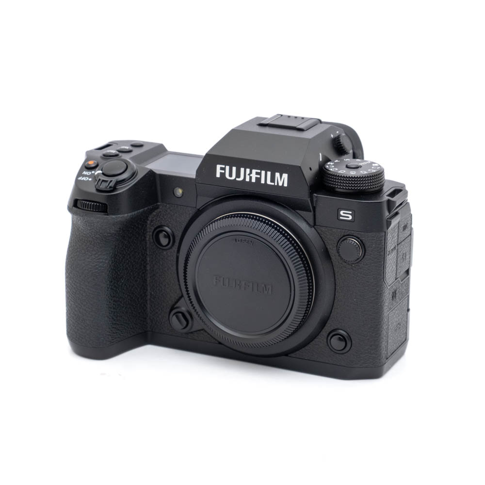 Fujifilm X-H2s-2045-1 Käytetty Fujifilm X-H2s -digitaalikamerarunko (SC 10000, K5, 12 kuukauden takuu, alv 24 %) on esitetty kolmivartalokuvassa ilman objektiivia; siinä on musta viimeistely, näkyvät valintakiekot ja kuvioitu kahva.