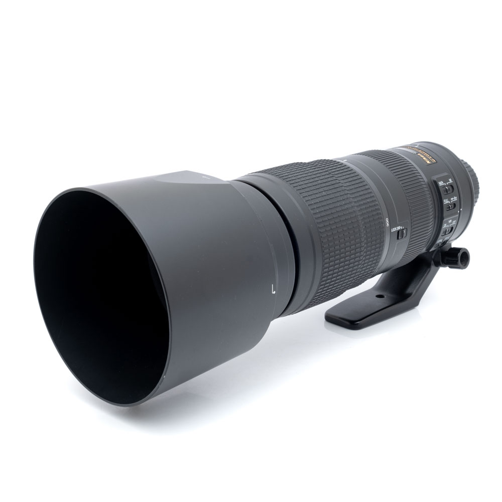 Nikkor 200-500mm f5.6ED-1 Suuri musta Nikon AF-S Nikkor 200-500mm f/5.6E ED VR -teleobjektiivi (käytetty), jossa on vastavalosuoja, jalustapanta ja ohjauskytkimet tynnyrissä, kuvakulmasta katsottuna.