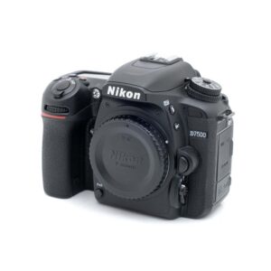Nikon D7500-1 Nikon D7500 (SC 28000) - Käytetty DSLR-kameran runko ja objektiivin suojus etupuolelta valkoisella taustalla.