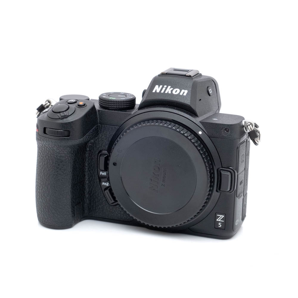 Nikon Z5-1 Nikon Z5 (K5, SC 2500) - Käytetty peilitön kamerarunko on kuvassa mustana, hieman oikealle päin, objektiivin kiinnityssuojus kiinni ja ilman objektiivia.